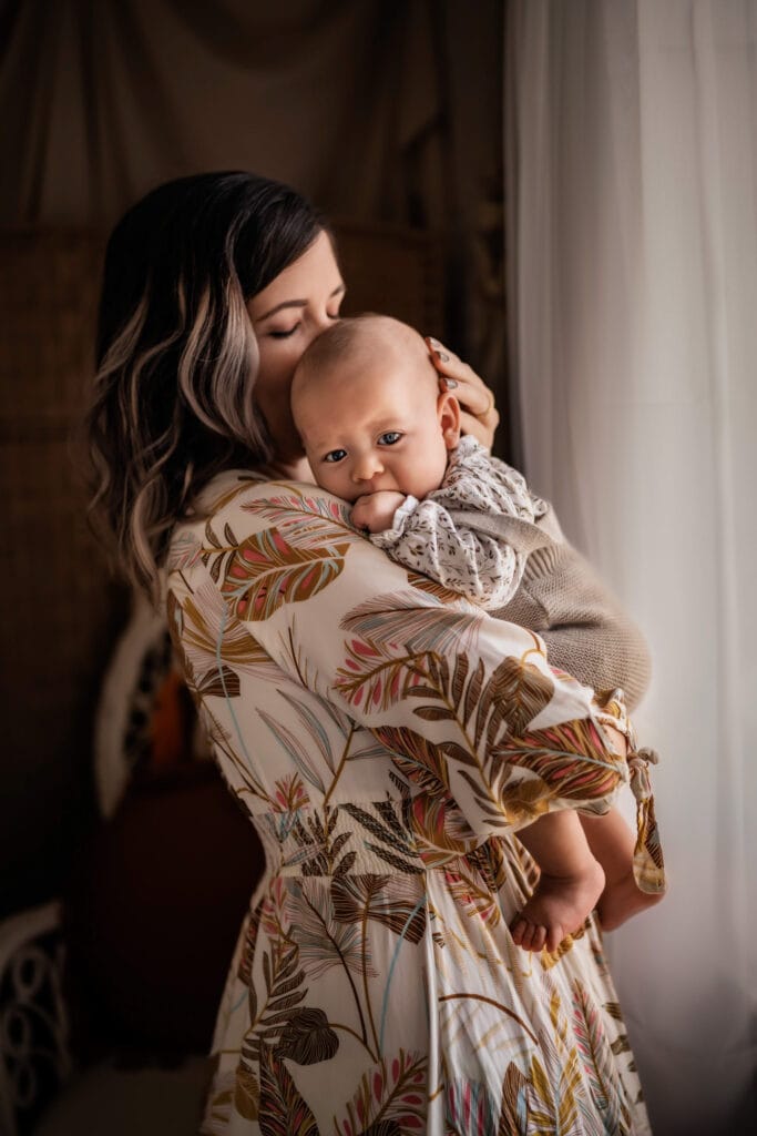 Family Photographer, a mother holds her baby inside their home